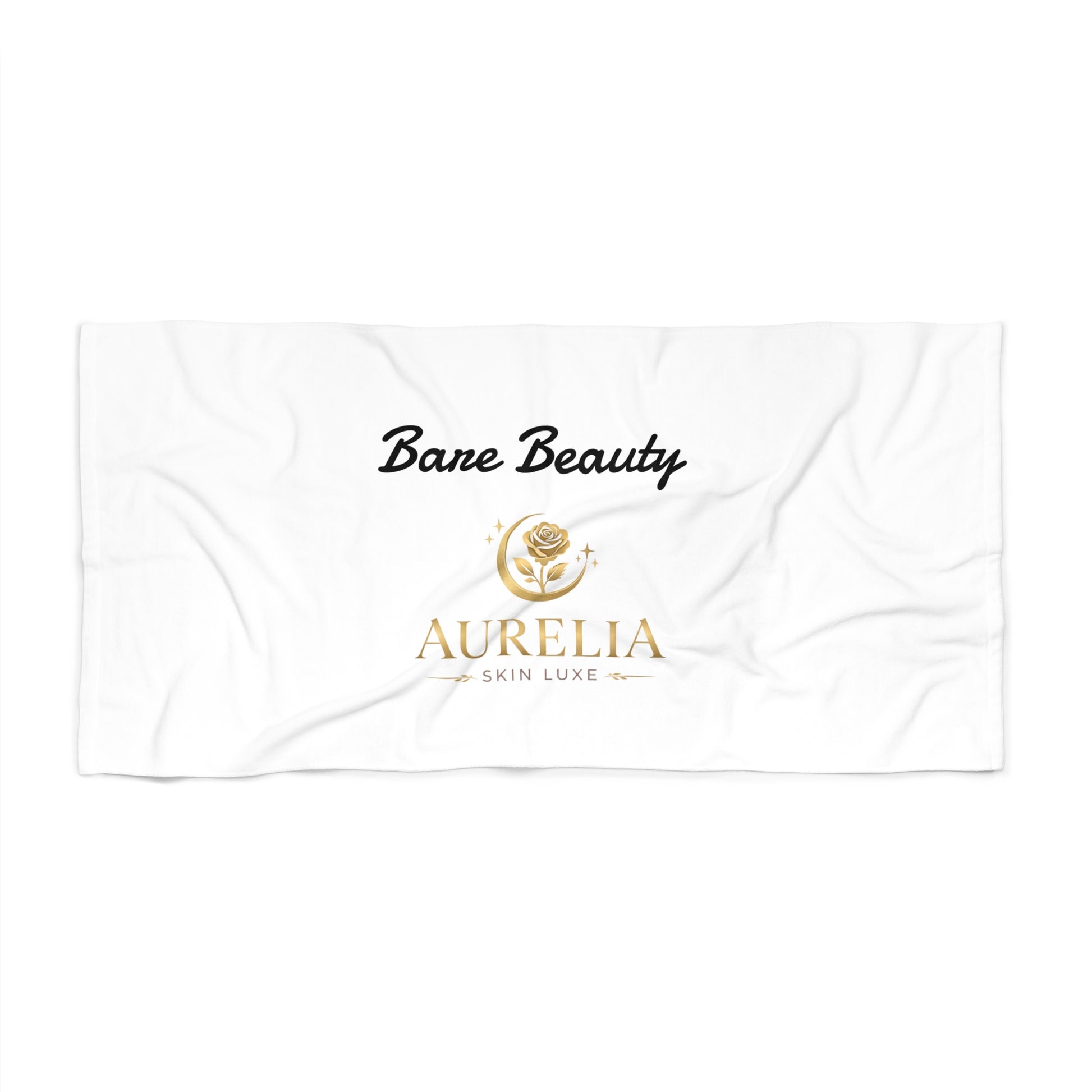 White towel with 'Bare Beauty' and 'Aurelia Skin Luxe' branding on a white background