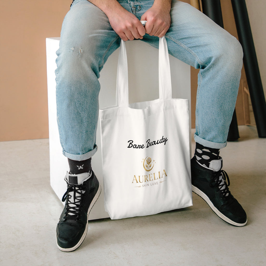 Person holding a white tote bag with text, wearing jeans and black sneakers.