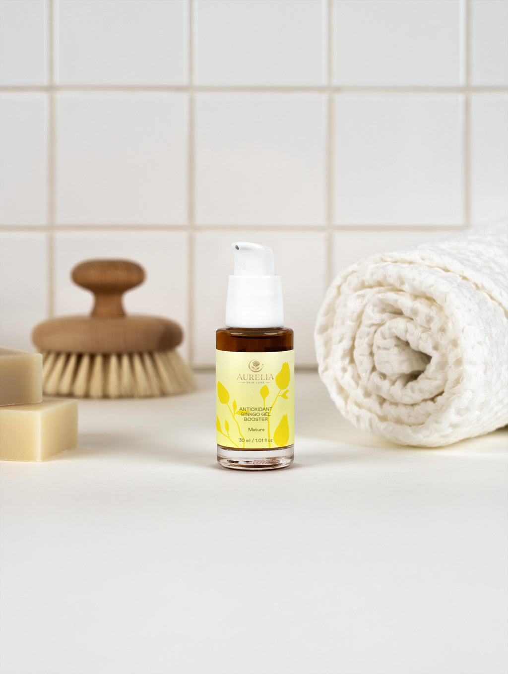 Skincare serum bottle with a brush and towel on a bathroom counter
