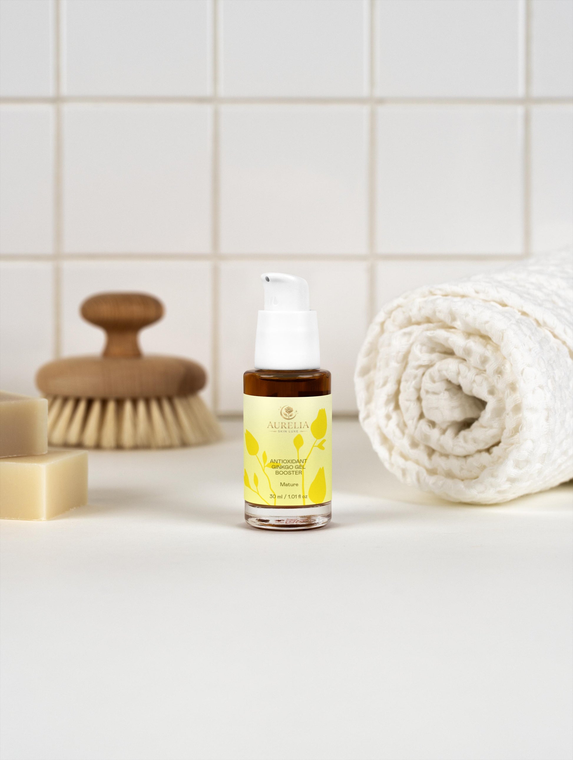 Skincare serum bottle with a brush and towel on a bathroom counter